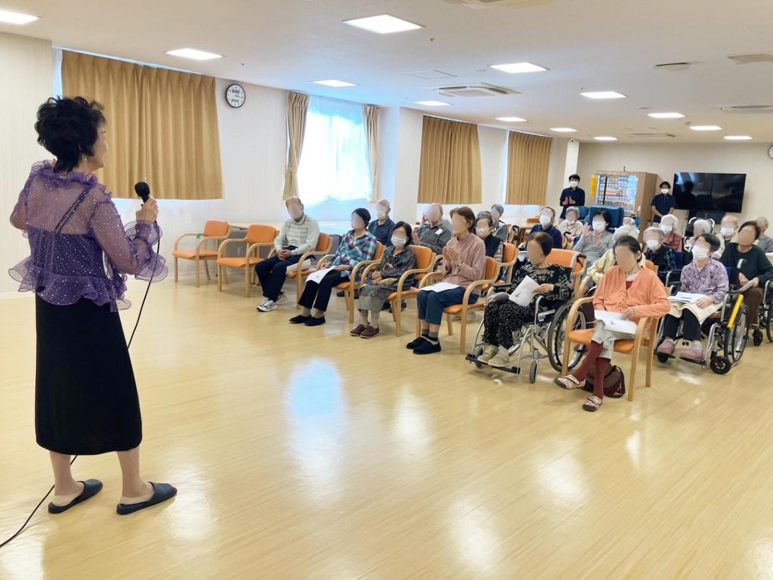 介護施設でのレクリエーション行事。スタッフが入居者に向けて演技・講演を行っている場面。