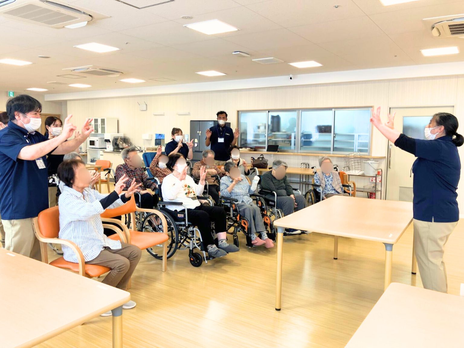 介護施設でのレクリエーション。スタッフと入居者が一緒に手拍子で楽しむ様子。
